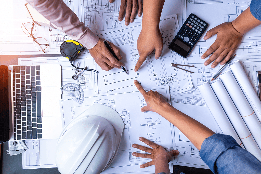 Les artisans d'un chantier calculent les besoins en materieaux devant un plan d'architecte.